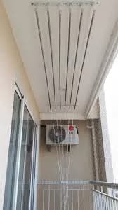 Ceiling cloth hanger rods above an outdoor AC unit on a narrow balcony